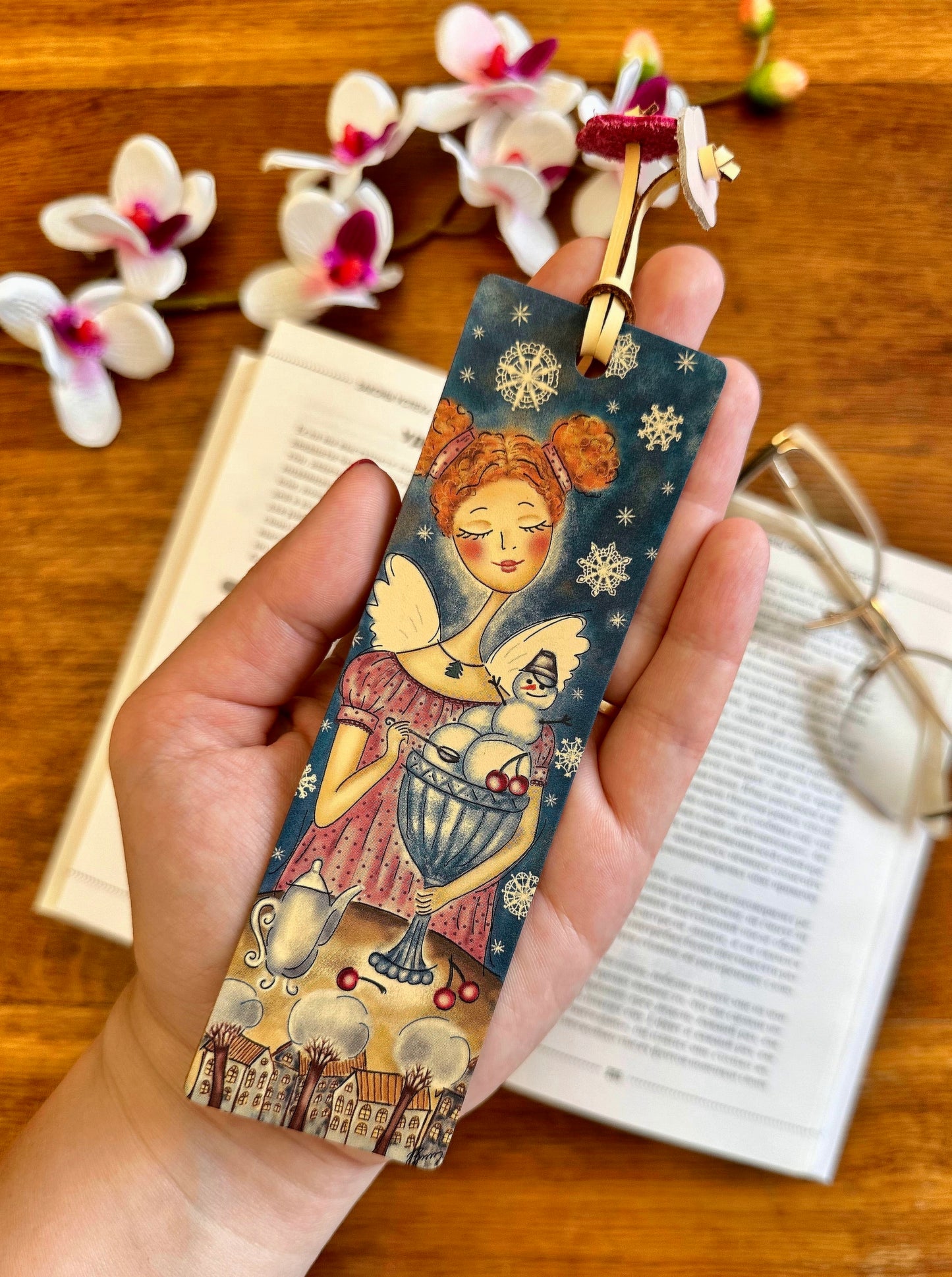 Leather bookmark with floral print laying on a wooden table, showing off its high-quality craftsmanship and design