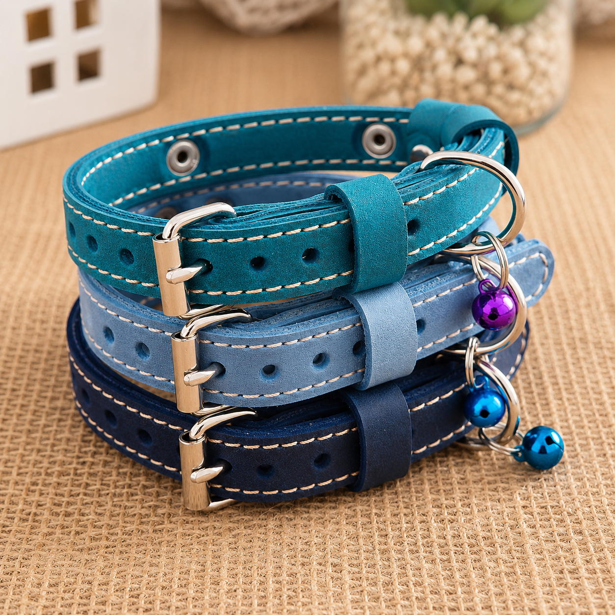Stack of blue leather dog collars with metal buckles and beads on a textured surface