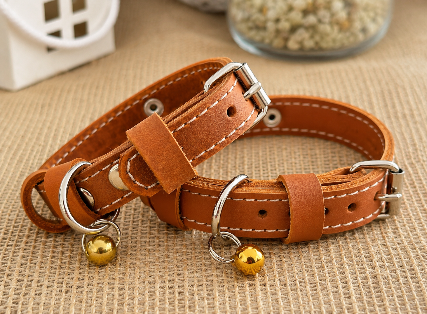 Brown leather dog collar with gold bell on a textured surface
