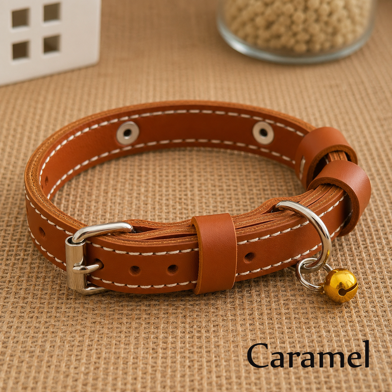 Brown leather dog collar with a gold bell on a beige fabric background