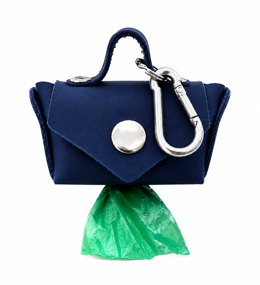 A navy blue dog poop bag holder with a silver snap button and carabiner, shown with a green plastic bag inserted, on a white background.