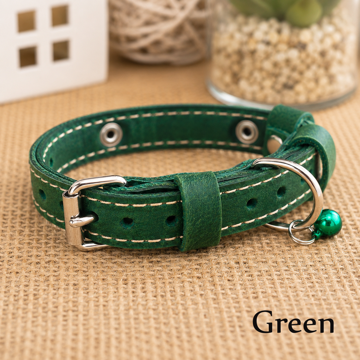 Green leather dog collar with silver hardware on a textured surface