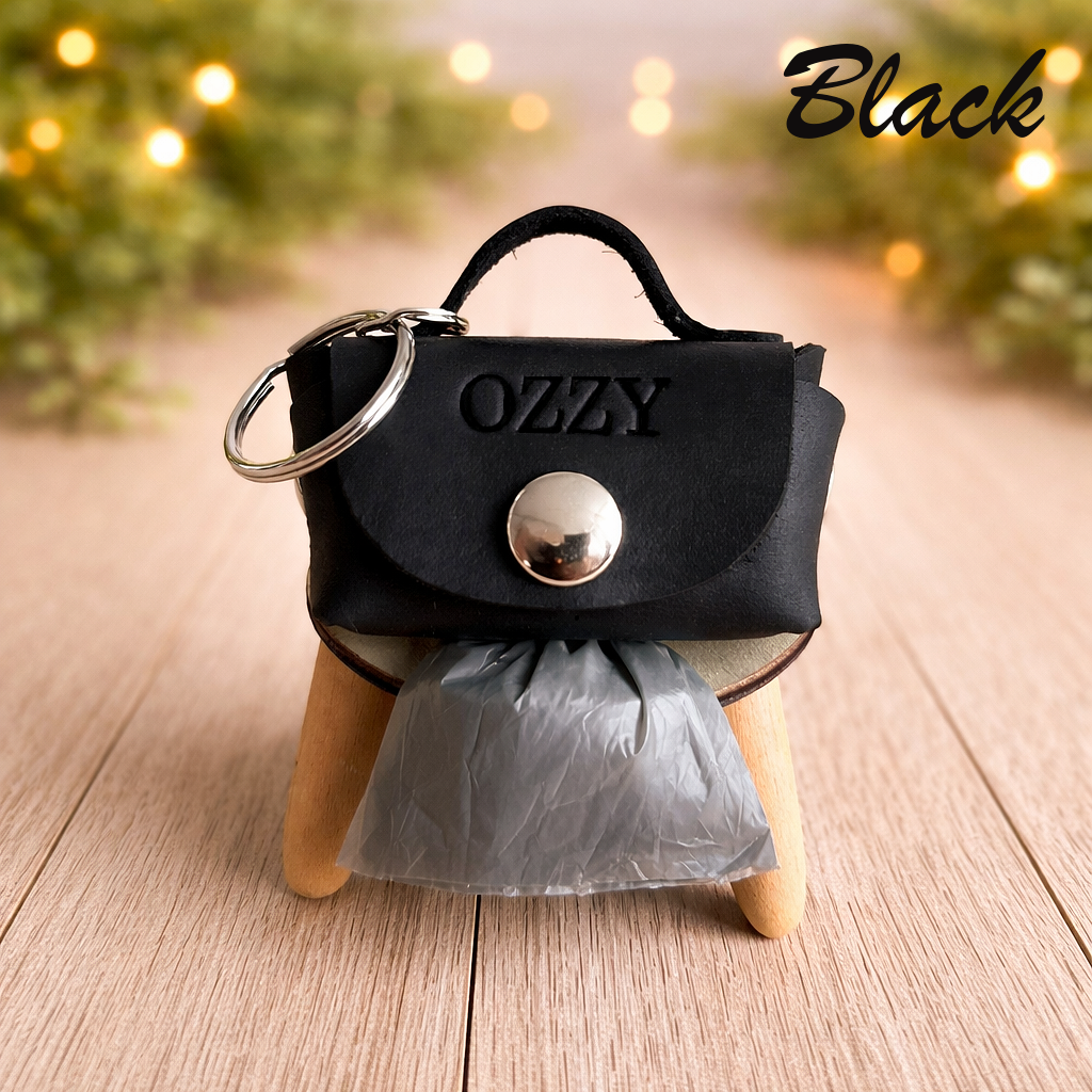 Black handbag-shaped keychain with 'OZZY' branding on a wooden surface.