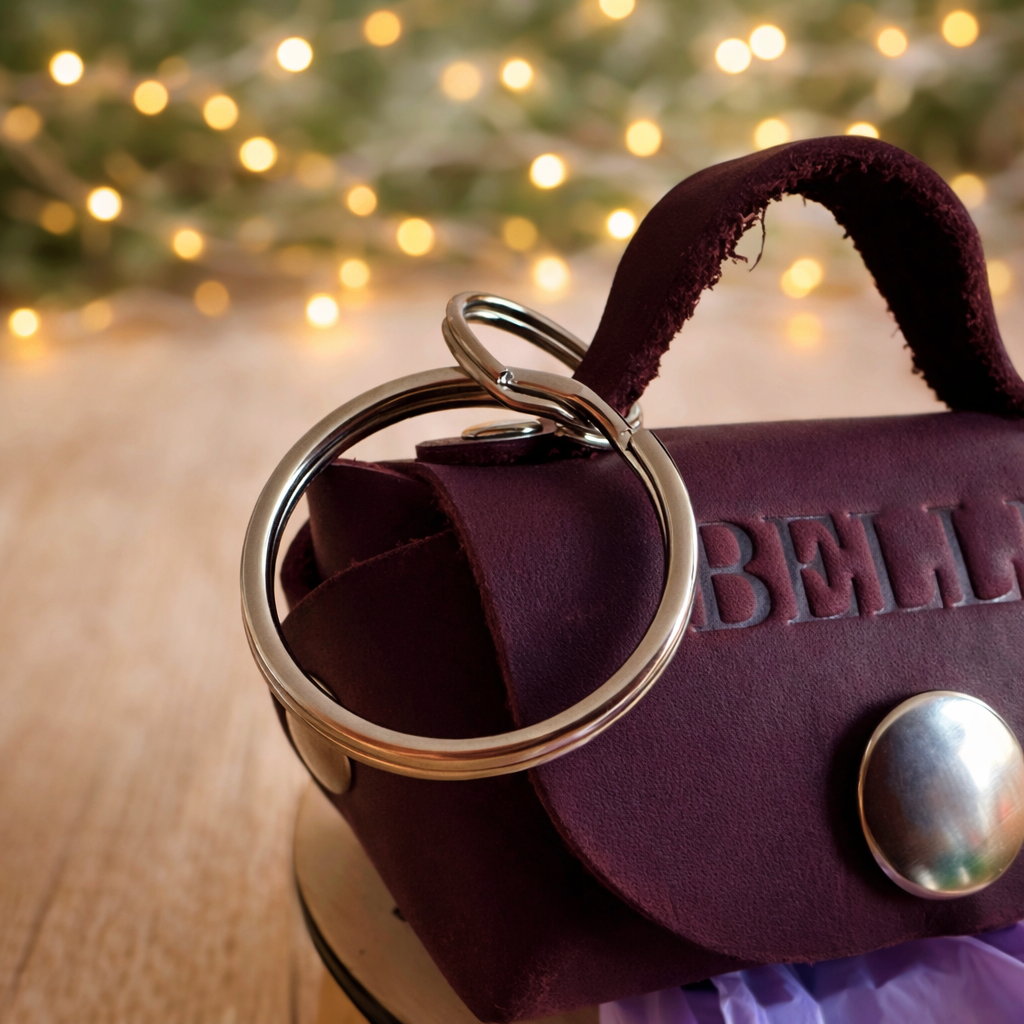 Purple leather bag with a keychain on a wooden surface with blurred lights in the background