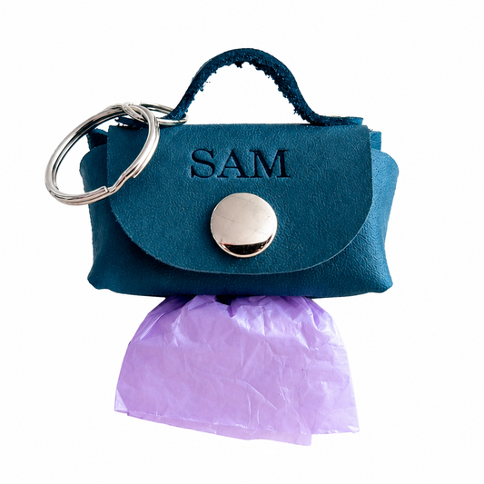 Blue handbag-shaped keychain with 'SAM' engraving on a white background