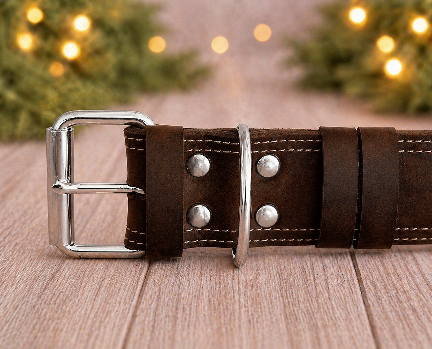 Brown leather belt with silver buckle on a wooden surface with blurred lights in the background