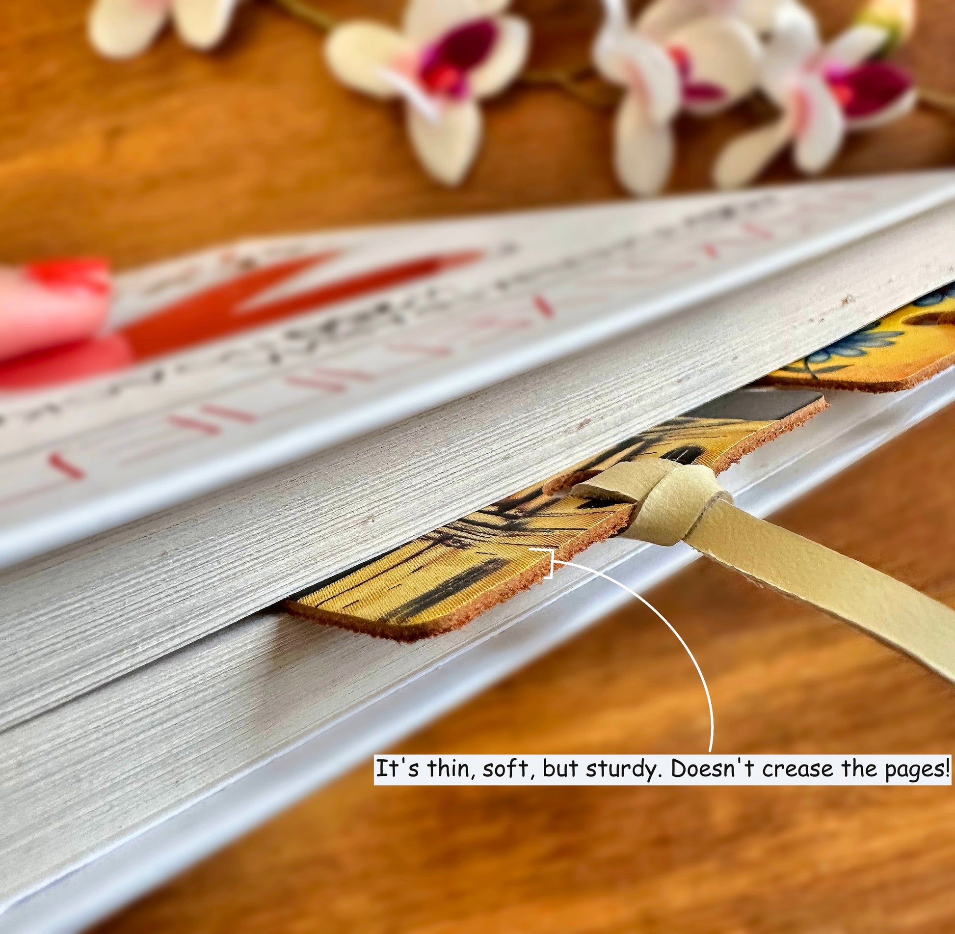 Leather bookmark with floral design resting on a wooden surface, showcasing its natural beauty and intricate details