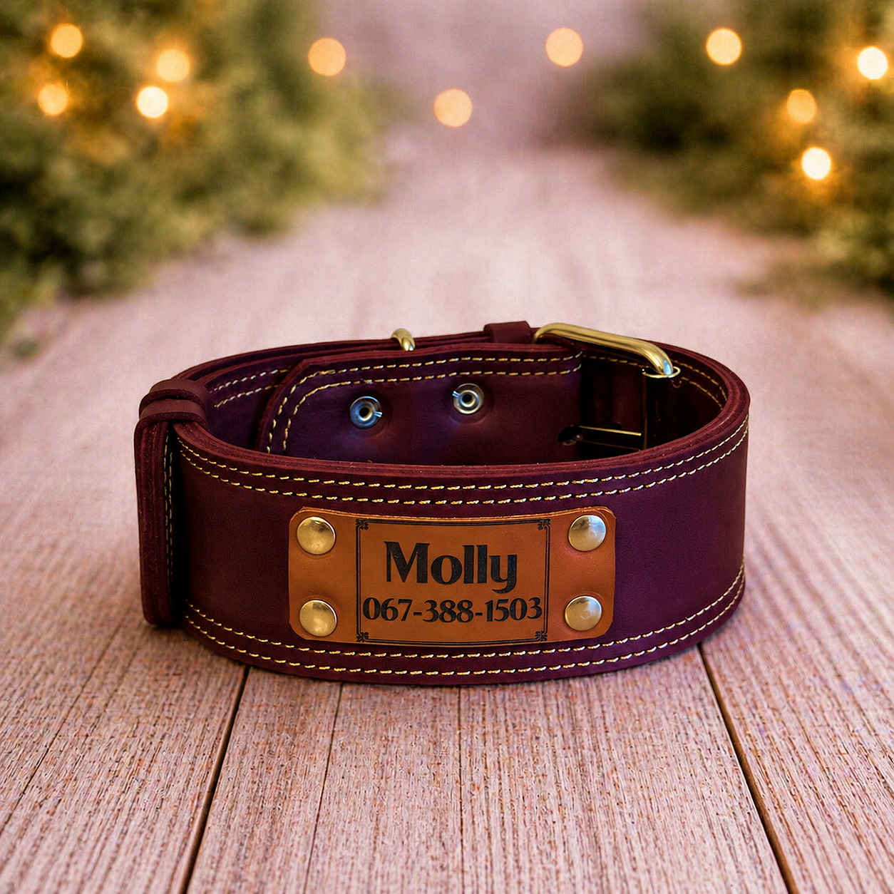 Brown leather dog collar with a nameplate on a wooden surface, Christmas lights in the background.