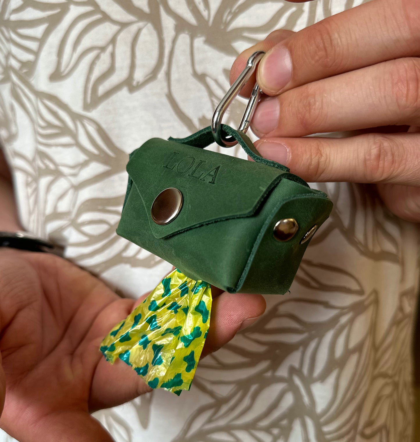 Close-up detail of the leather poop bag dispenser with an attached bell for added convenience
