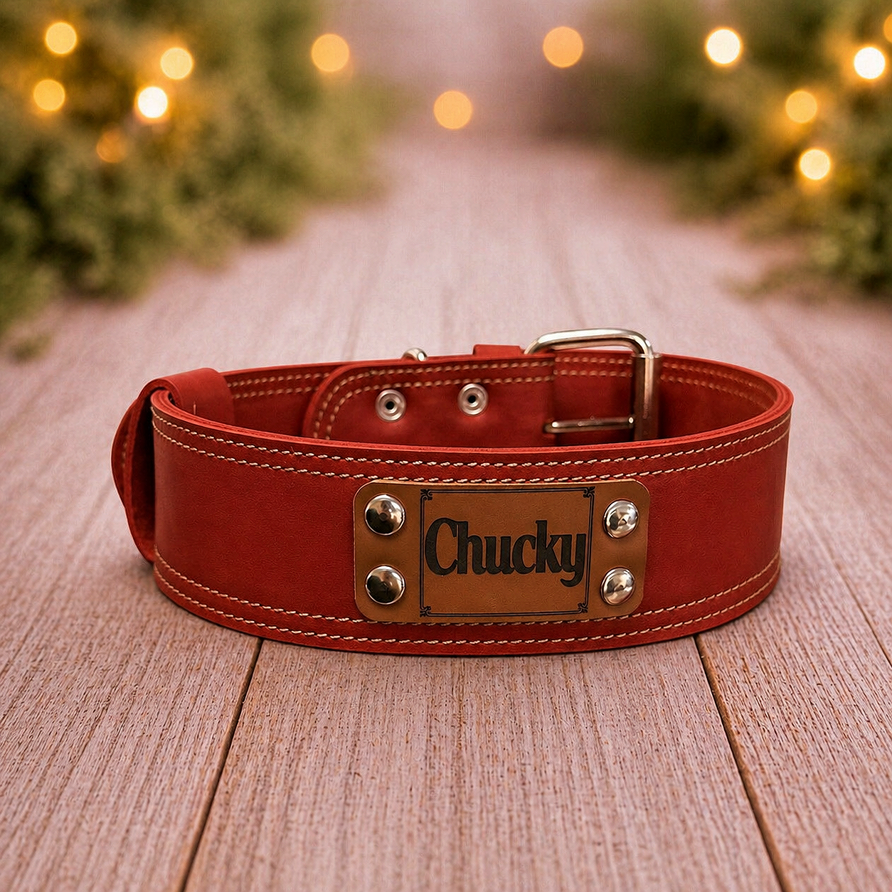 Red leather dog collar with 'Chucky' tag on a wooden surface, Christmas lights in the background
